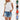 A women's fashion ensemble featuring a white pleated high neck blouse paired with distressed denim shorts.