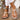 Women's white rhinestone flat strappy ankle sandals on a person's foot, showcasing a stylish and fashionable design.
