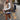 Women's white shearling vest styled with urban chic winter fashion, featuring visible shoulder and sleeve detail, worn by a model possibly with eyewear against a natural backdrop.