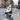 Woman wearing a white shearling vest standing outdoors in an urban setting.