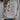 Women's white sweatshirt featuring a "Let It Be" feather print in a bohemian style, paired with jeans. The sweatshirt has long sleeves and a round neckline, embodying a casual yet fashionable look.