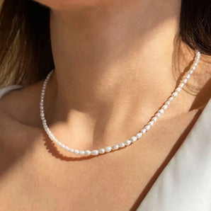 Close-up of a person wearing a 14K gold clasp 3mm pearl necklace, adjustable and hypoallergenic, emphasizing the elegant details on the neck and complemented by subtle body features.