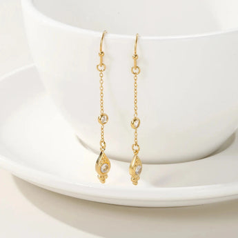 18K gold plated drop earrings with cubic zirconia displayed on a reflective surface, showcasing intricate design and luxurious sparkle.