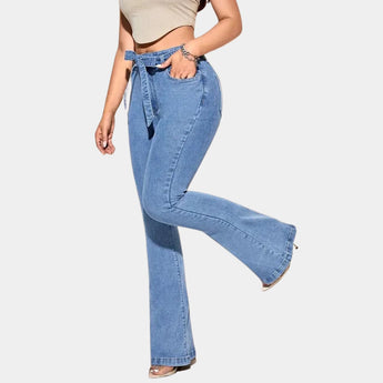 
A person wearing 70s vintage high-waisted flared bell bottom jeans paired with a dress shirt, standing with hands on hips and wearing sunglasses.