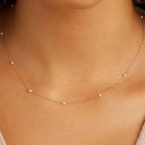 Elegant woman wearing a hypoallergenic gold-plated 925 sterling silver pearl necklace, showcasing the piece against her beige dress, highlighting the necklace’s placement on the neck and chest area.
