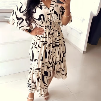 Plus size woman wearing an abstract print V-neck summer dress with a ruffle hem, showcasing the dress's flattering fit around the shoulders, waist, and thighs.