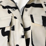 Abstract print women's cropped jacket in black and white featuring a drawstring waist, with a jersey-like texture, long sleeves, and a stylish collar.