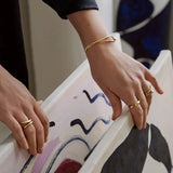 A hand wearing an adjustable minimalist two-tone silver and gold ring, showcasing sleek modern jewelry design.