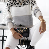 A person wearing a gray animal print sweater, ripped white jeans, lace-up combat boots, and carrying a designer bag.