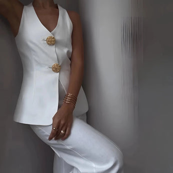 Black asymmetric jumpsuit with gold buttons, featuring a formal style with long sleeves and a structured collar.