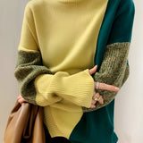 Asymmetric two-tone turtleneck sweater in green, featuring ribbed cuffs and a unique design that highlights the neck and shoulder area. The sweater is showcased on a mannequin, emphasizing its fashion-forward style and comfortable fit suitable for various body types.