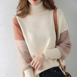 Asymmetric two-tone turtleneck sweater in orange and white, featuring ribbed cuffs and long sleeves, displayed on a model.