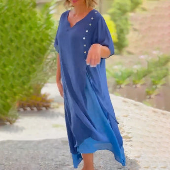Asymmetrical blue V-neck maxi dress with side buttons, featuring a sleeveless design and a flowing silhouette, perfect for summer fashion.