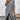 Asymmetrical grey ribbed turtleneck sweater dress featuring long sleeves and a knee-length hem, suitable for winter fashion, displayed on a standing model.
