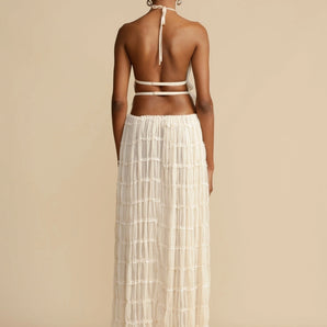 Elegant backless crop top paired with a tiered maxi skirt, worn by a woman, showcasing the shoulder, arm, and waist, ideal for a stylish summer evening.
