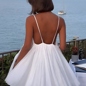 Backless white summer dress featuring elegant resort wear design suitable for beach and yacht, displayed against a backdrop of blue sky and water, highlighting its sleeveless and waist-accentuating style.