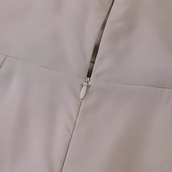 Beige adjustable strap cami with a zipper, featuring a minimalist design suitable for summer fashion.