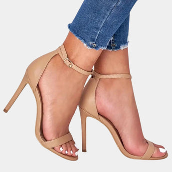 Beige ankle strap stiletto heels in apricot color, featuring an elegant platform design, worn on a model's foot.