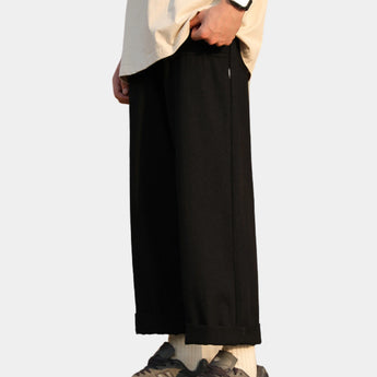 A person wearing beige baggy high-waisted wide-leg trousers paired with a black top, showcasing a casual streetwear style.