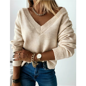 Beige chunky knit V-neck sweater worn by a woman, styled with jeans, focusing on the upper body and arms, showcasing autumn fashion for women in a casual setting.