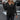 A woman wearing a black XXL crew neck sweater, showcasing a casual fall fashion look. She is standing with her arms relaxed, highlighting the sweater's comfortable fit on her shoulders and waist. The sweater features long sleeves and is suitable for a stylish, cool-weather outfit.