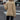 Woman wearing a beige crew neck sweater with long sleeves, styled as a casual fall fashion pullover. She is standing and has long hair, possibly wearing eyewear. The sweater is designed for women's fashion, highlighting the neckline and shoulder area.