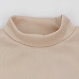 Beige crew neck t-shirt made from soft cotton, featuring minimalist design and short sleeves, displayed on a wooden background.