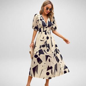 Beige geometric midi dress featuring a V-neckline and cinched waist, displayed on a mannequin in a well-lit setting. The dress is designed with short sleeves, highlighting summer fashion trends.