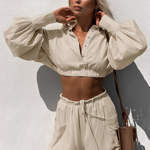 Woman wearing beige linen crop top with short sleeves and high-waisted drawstring shorts, showcasing summer fashion.