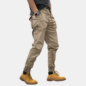 Men's slim fit cargo pants in beige featuring a durable design with multiple pockets, suitable for outdoor use.