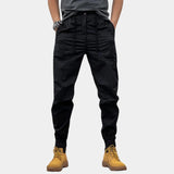 Men's black slim fit cargo pants with multiple pockets, designed for outdoor wear. The pants are shown in a 3XL size, highlighting the durable fabric and fashion-forward design.