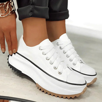 Beige platform sneakers with chunky sole and star heel detail, worn by a woman, styled for streetwear.