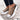 Beige platform sneakers with chunky sole and star heel detail, featuring a striped tiger design, worn by a woman in streetwear fashion.