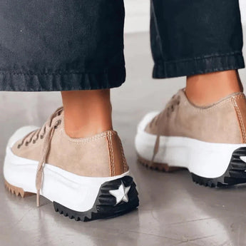 Beige platform sneakers with chunky sole and star heel detail, worn by a woman; streetwear fashion.