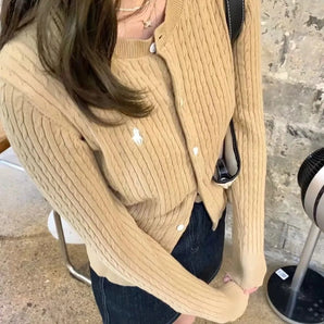 Beige ribbed knit button-down cardigan worn by a woman with sunglasses, showcasing a fall fashion look. The cardigan has long sleeves, and the woman is styled in a casual yet trendy outfit suitable for cooler weather.