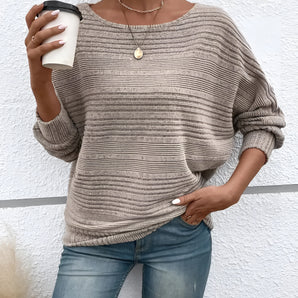 Woman wearing a beige ribbed knit pullover sweater, paired with jeans.