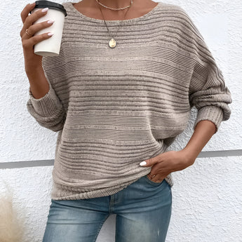 Woman wearing a beige ribbed knit pullover sweater, paired with jeans.