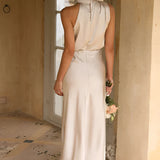 Beige sleeveless backless midi dress featuring a fitted waist and elegant design suitable for weddings and cocktail events.