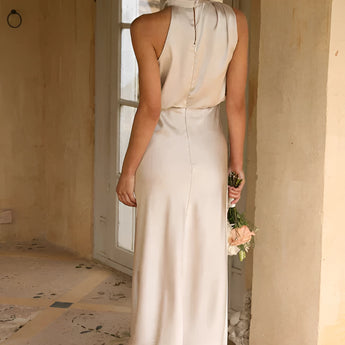 Beige sleeveless backless midi dress featuring a fitted waist and elegant design suitable for weddings and cocktail events.