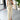 Beige sleeveless belted jumpsuit displayed on a hanger, featuring a chic summer design with a belt at the waist, set against a neutral background with a potted plant nearby.