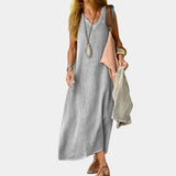 Beige sleeveless linen maxi dress with an elegant A-line silhouette, perfect for summer occasions. The dress features a flowing design that extends to the ankles, highlighting the waist.