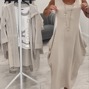 Beige sleeveless linen midi dress with a round neck and elegant, casual summer fashion design, displayed on a standing model.