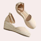 Beige suede espadrilles featuring closed toe wedge design with ankle strap, highlighting a blend of fashion and comfort.