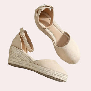 Beige suede espadrilles featuring closed toe wedge design with ankle strap, highlighting a blend of fashion and comfort.