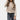 Beige women's bouclé double-breasted blazer with long sleeves and a structured collar, worn over a grey dress shirt and paired with denim jeans, showcasing chic fall outerwear style.