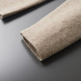 Beige women's collarless open front linen blazer displayed on a grey wooden flooring background.