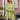 
A woman wearing a green oversized batwing poncho sweater stands indoors. She has an elegant hairstyle and is accessorized with sunglasses. The setting includes a window and houseplants, giving a cozy and stylish fall fashion vibe.