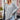
A woman modeling a gray oversized batwing poncho sweater, ideal for fall fashion. She is wearing sunglasses and standing outdoors, with a background featuring plants. The sweater is styled as outerwear and complements her hairstyle.