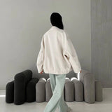Beige women's oversized fleece bomber jacket featuring a cozy and trendy design with long sleeves and a comfortable fit, perfect for winter fashion.