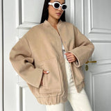 Beige women's oversized fleece bomber jacket with long sleeves, showcasing trendy winter fashion.